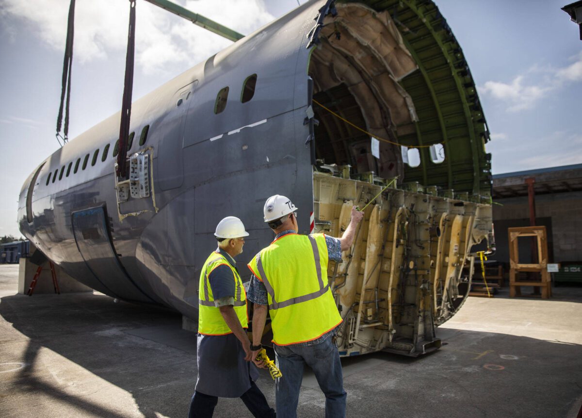 Brian Wilson, left, and Ron Fronheiser, right, survey the fuselage after it is placed at Edmonds College’s Advance Manufacturing Skill Center
